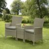 Rattan garden chairs with small table in a garden.