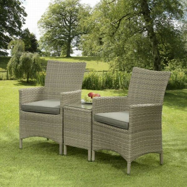 Rattan garden chairs with small table in a garden.