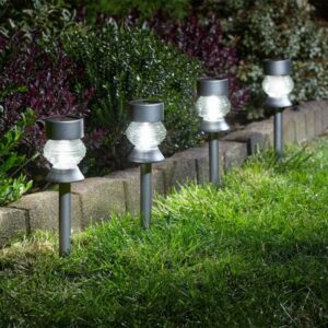 4 white stake lights in a garden.