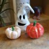 A ghost faced lantern made from clay and two clay pumpkins, one painted white and one orange.