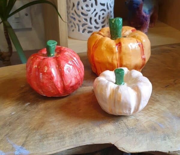 Three pumpkins made from clay in various sizes and colours.