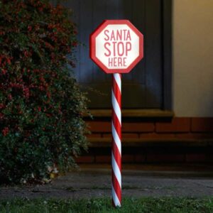 A red and white garden stake light that reads 'Santa Stop Here'.