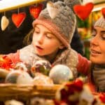 A child being held by an adult to look at Christmas baubles.